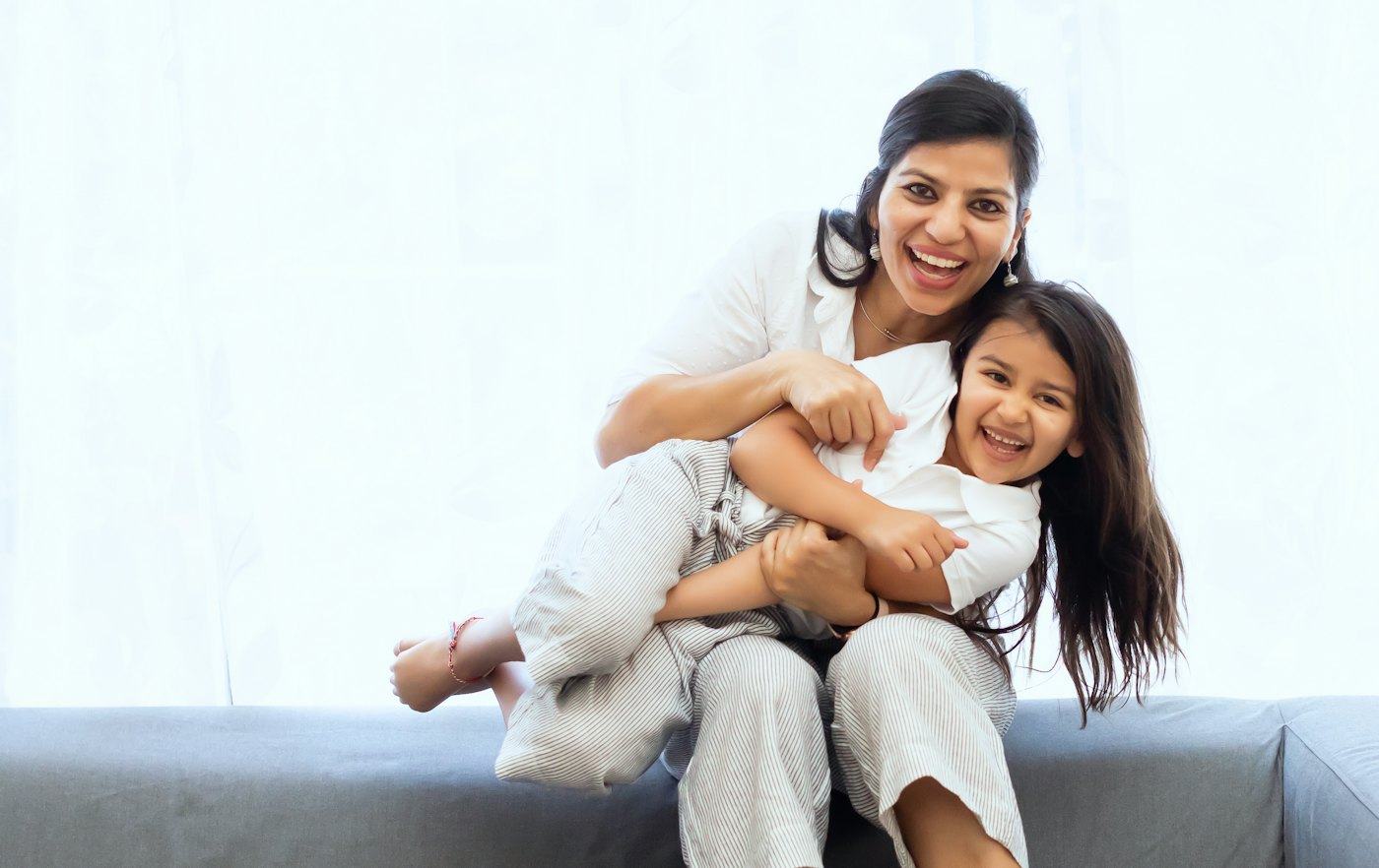 Madre e hija abrazadas y sonriendo en la sala de su casa